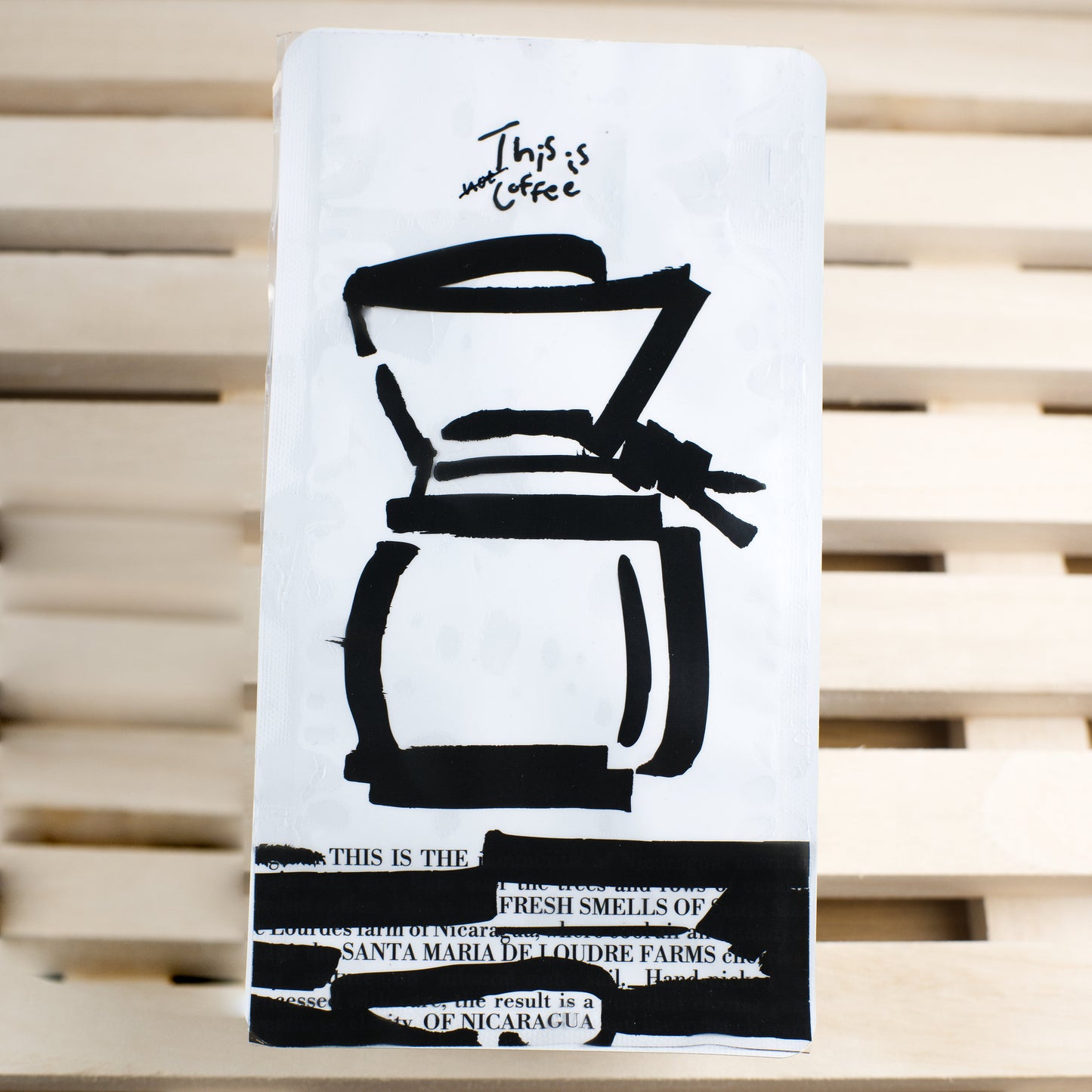 White coffee-themed coffee bag with black illustrations on a wooden surface