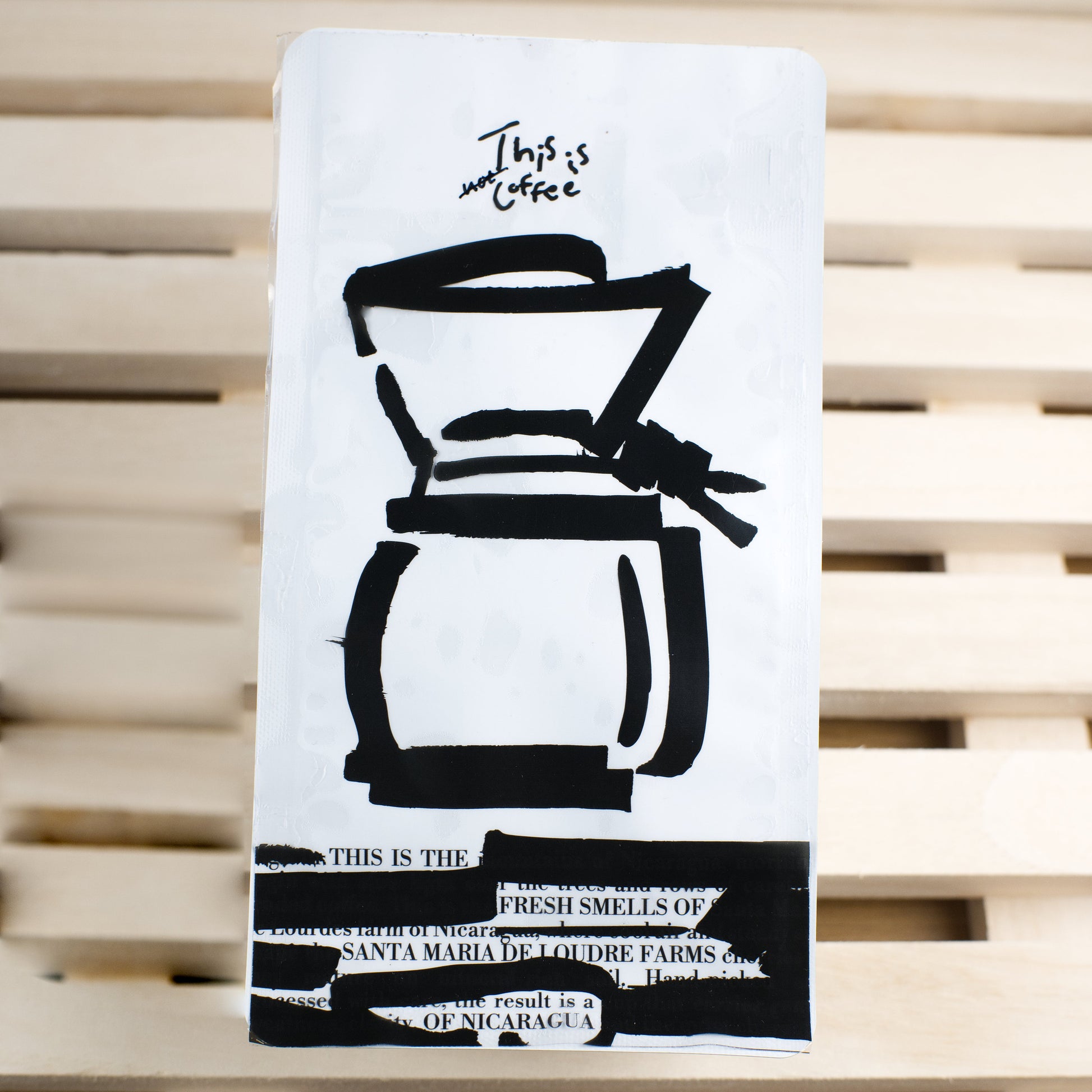 White coffee-themed coffee bag with black illustrations on a wooden surface