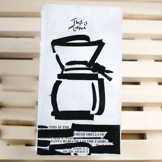White coffee-themed coffee bag with black illustrations on a wooden surface